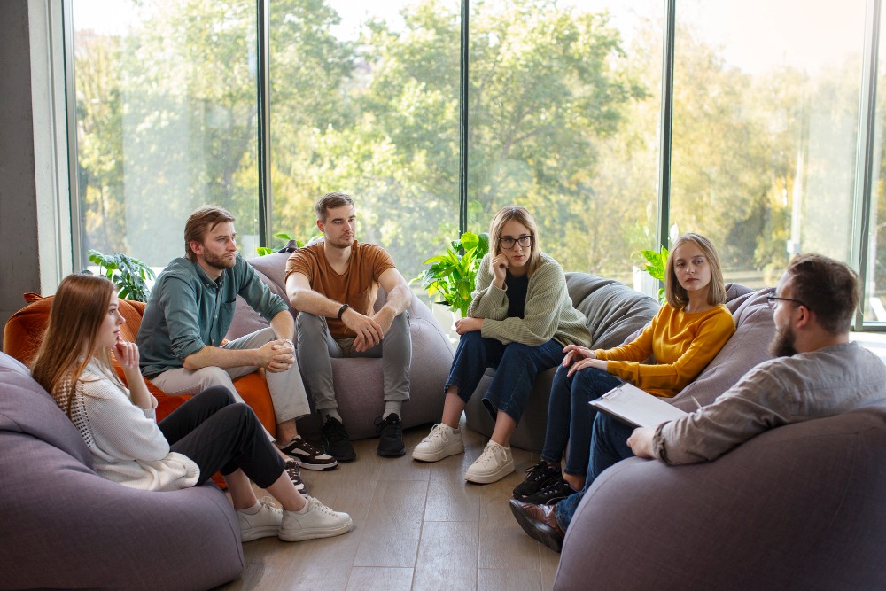 Group therapy session featuring individuals participating in a supportive behavioral health treatment discussion.